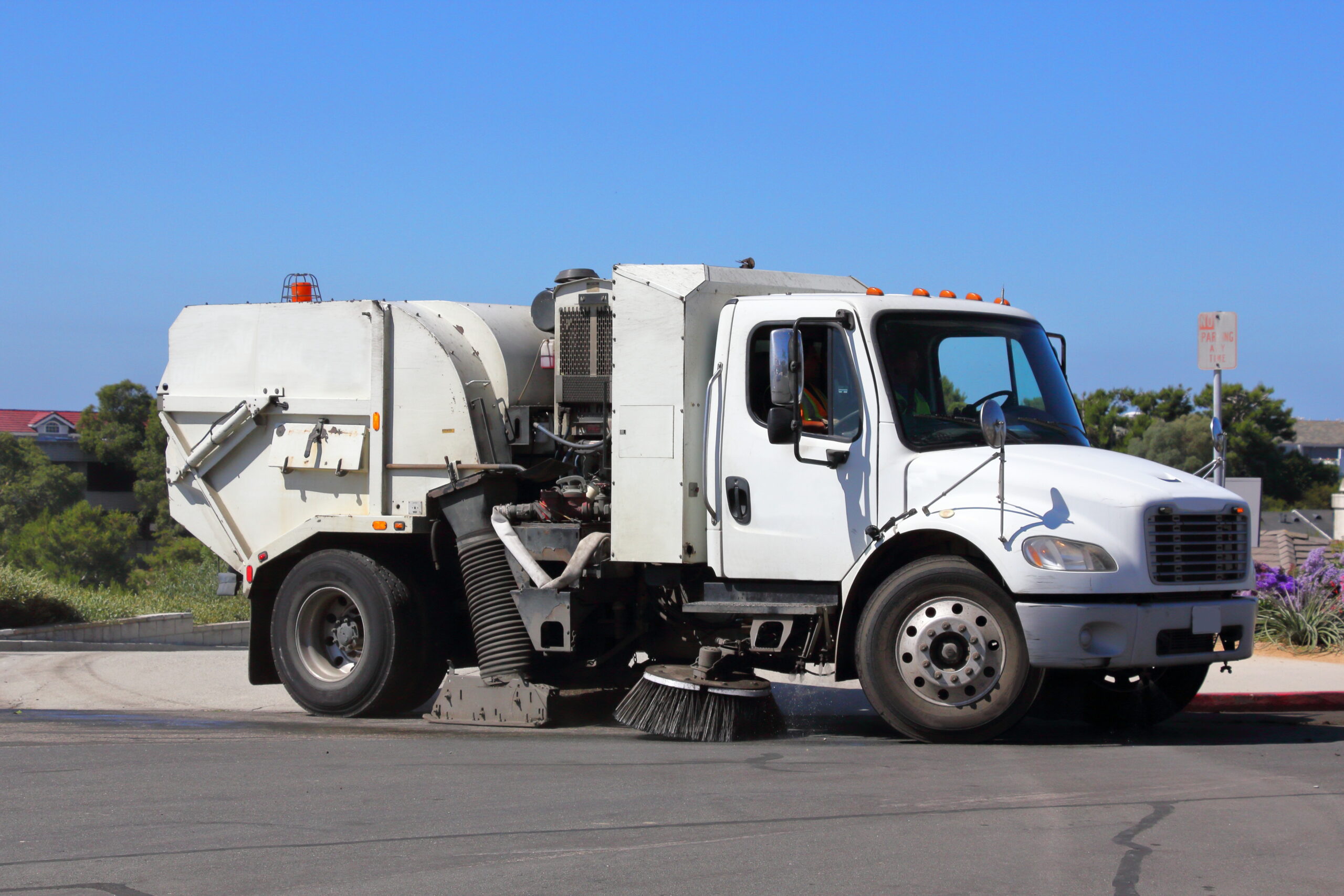 A city street sweeper, sweeping a street that drains into the ocean.
