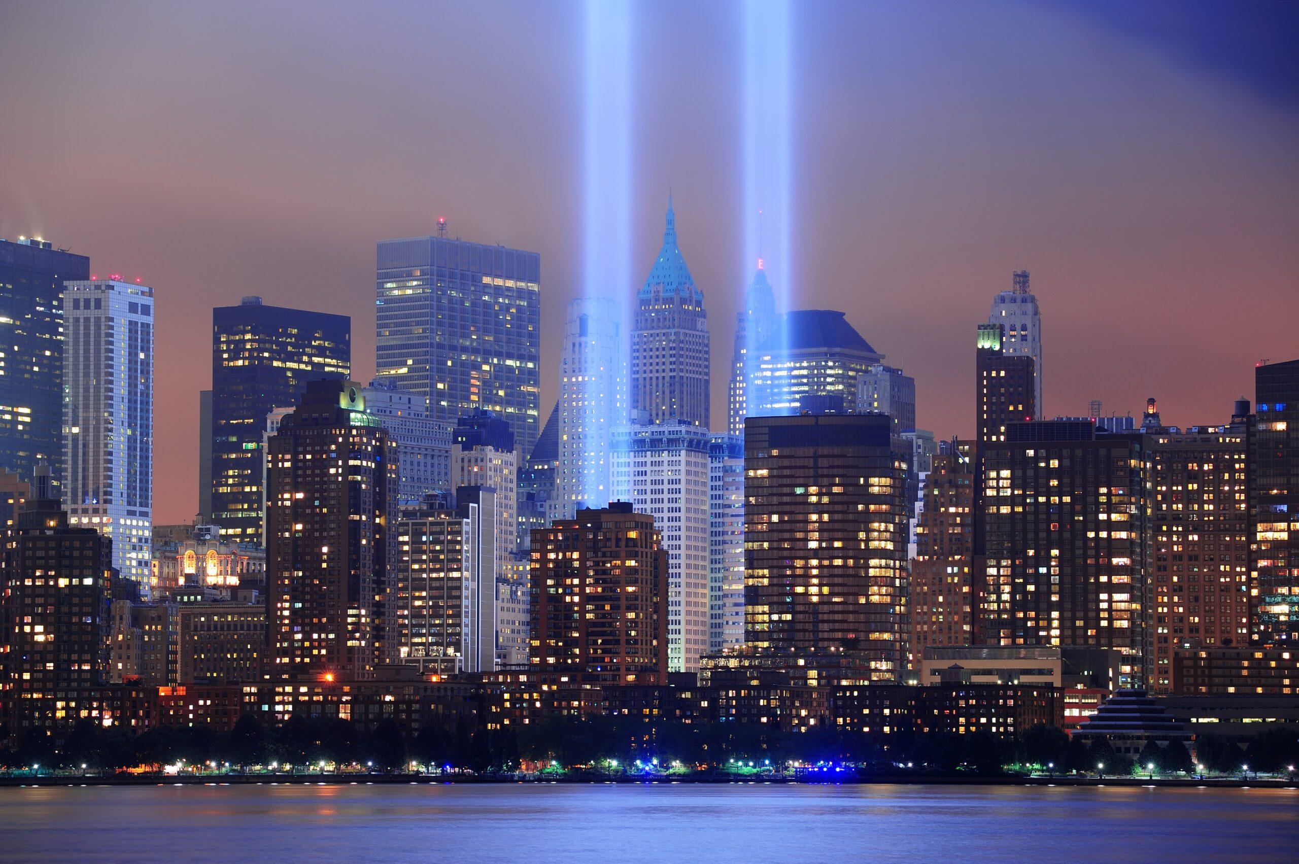 New York City Manhattan downtown skyline at night from Liberty Park with light beams in memory of September 11 viewed from New Jersey waterfront.